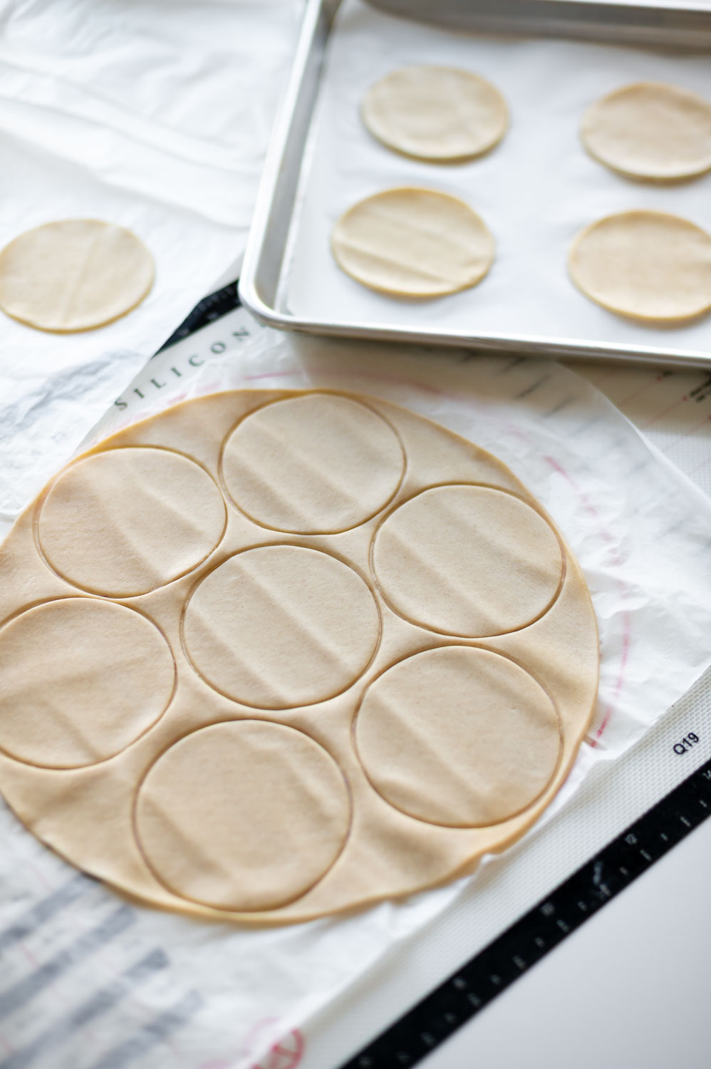 premade store bought pie dough is rolled out on a table with 3" rounds cut out of it to make easy cherry hand pies with