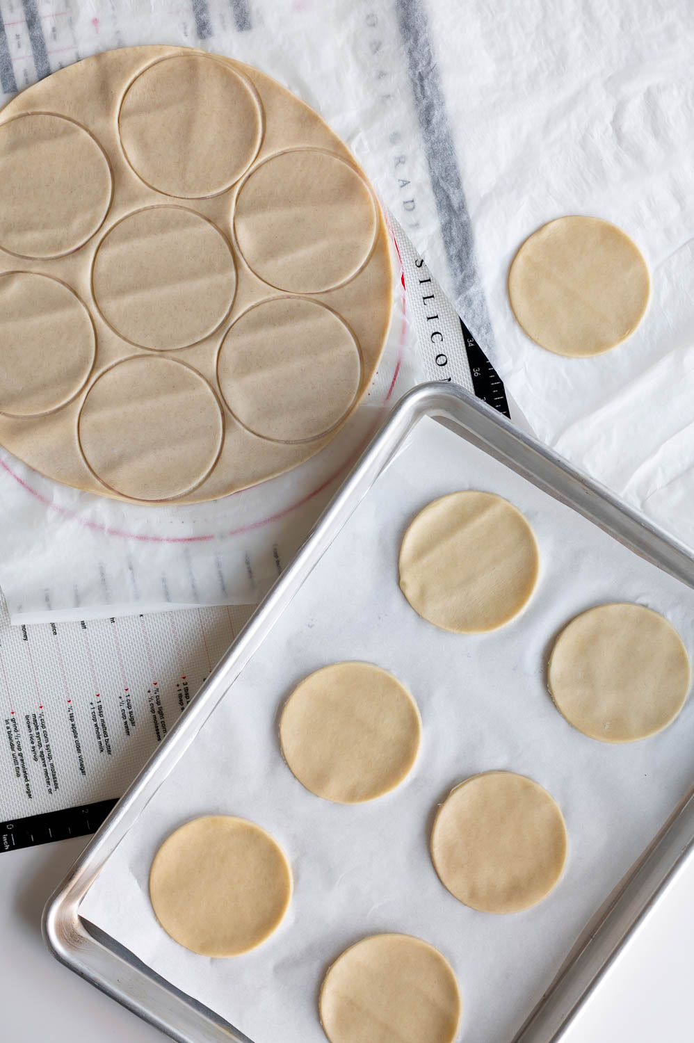premade store bought pie dough is rolled out on a table with 3" rounds cut out of it to make easy cherry hand pies with