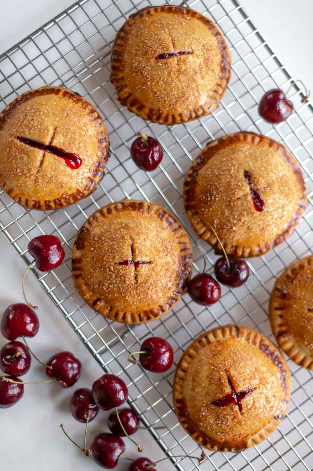 semi homemade cherry hand pie fresh out of the oven rest on a cooling rack next to fresh cherries