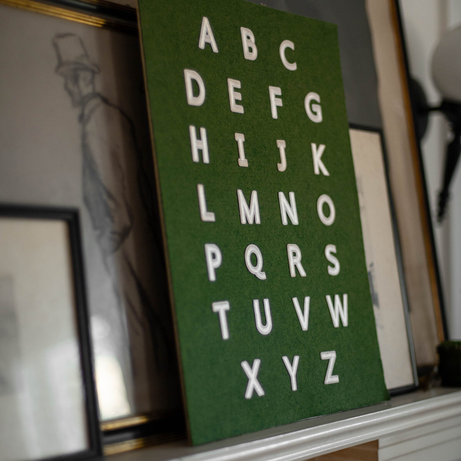 diy alphabet art made with white applique letters and green felt rests on an art ledge as vintage nursery wall decor.