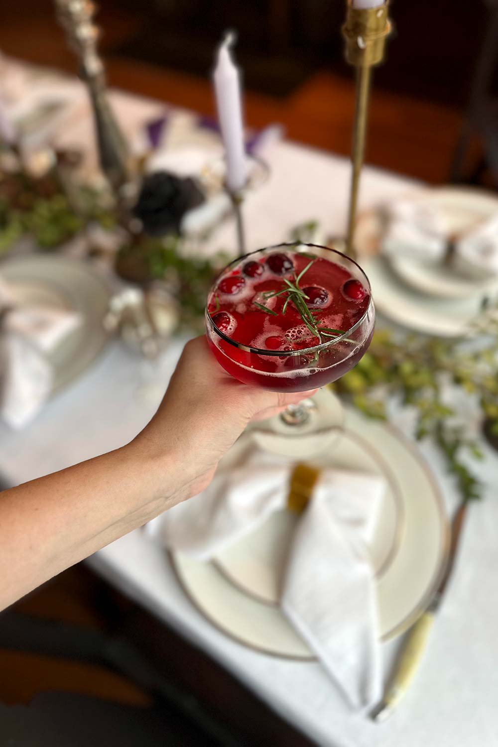 a woman holds a cocktail at a friendsgiving themed monthly supper club for freinds