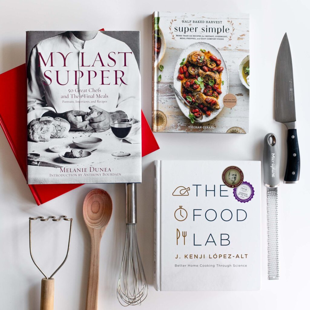 a flat lay with the best supper club cookbooks for supper club menu planning next to various kitchen tools