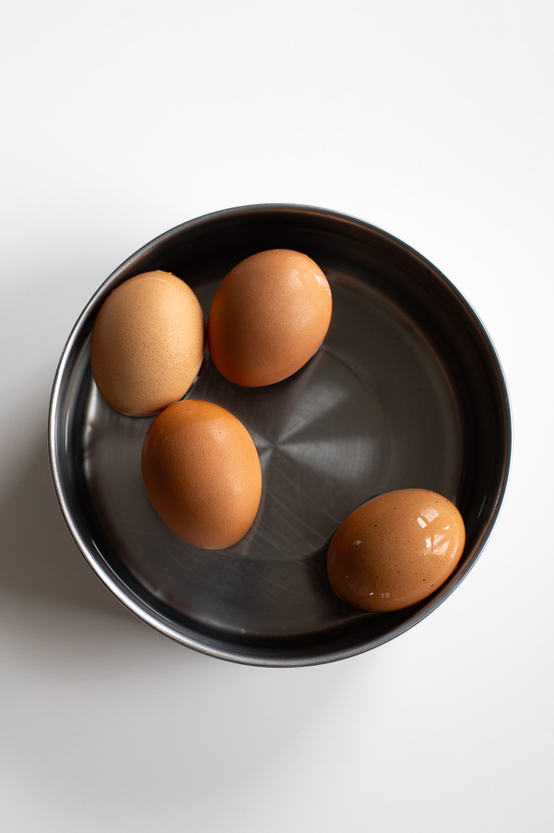 Brown eggs submerged in white vinegar to lighten shells for Easter dye