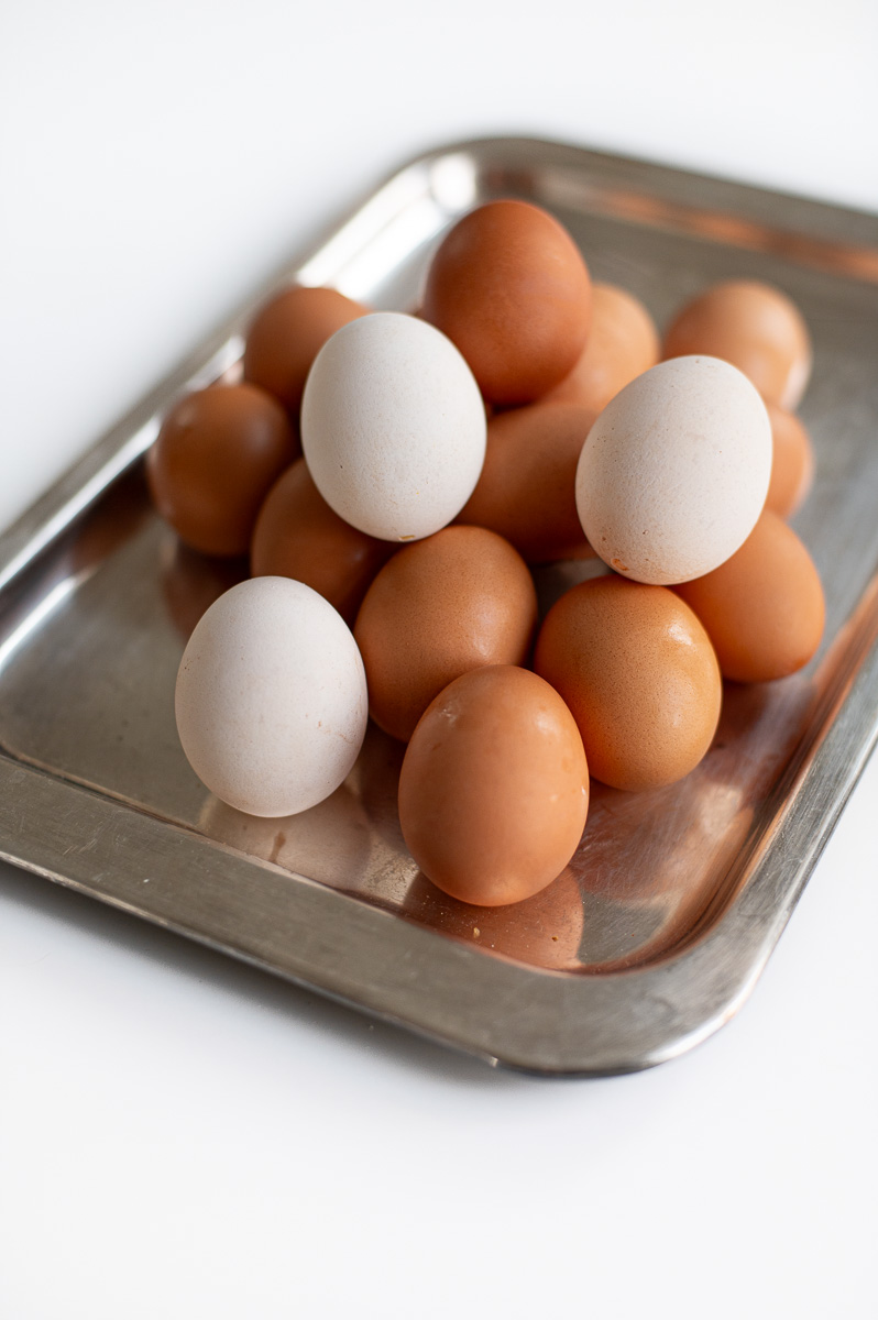Brown eggs and lightened brown eggs on a silver tray after soaking in vinegar for Easter dye