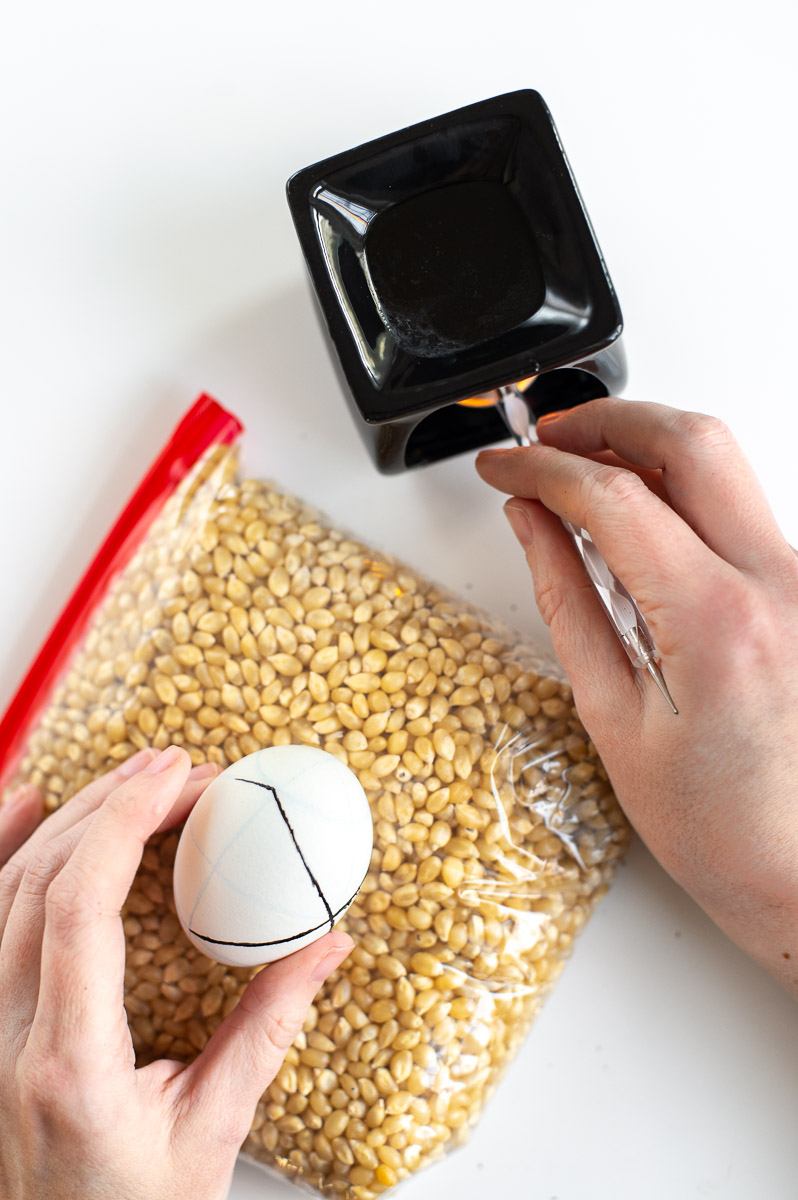 a woman shows how you can decorate pysanky without a kistka using hold melted crayon wax and an embossing stylus tool.