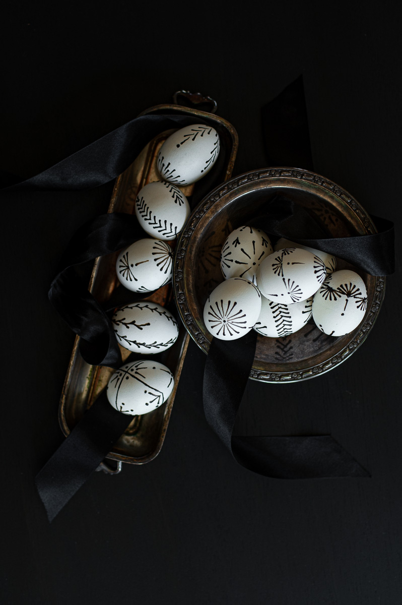 a collection of pin-drop, wax pull easter eggs sitting in silver dishes showcasing the array of designs you can make to decorate Easter eggs with crayon wax for easter.