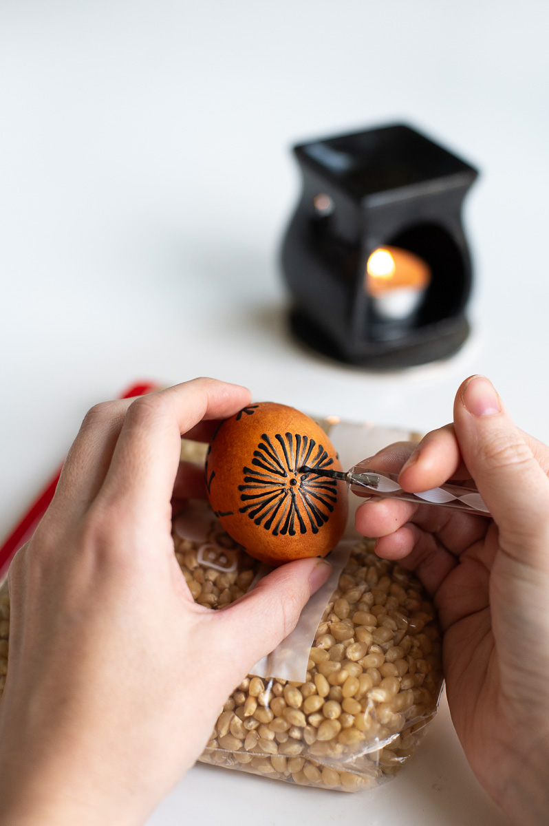 a woman applies a second round of wax to an easter egg after the first dye bath using traditional pysanky easter egg decorating methods without a kistka
