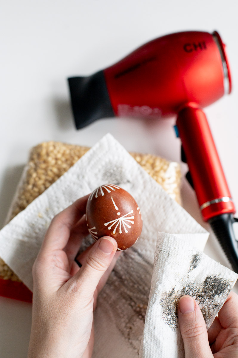 Removing wax from a DIY pysanky Easter egg to reveal the design