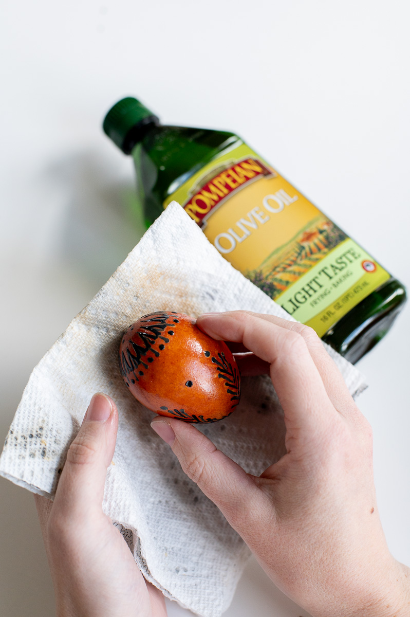 a woman rubs an egg down with olive oil to give it more shine and lustre.