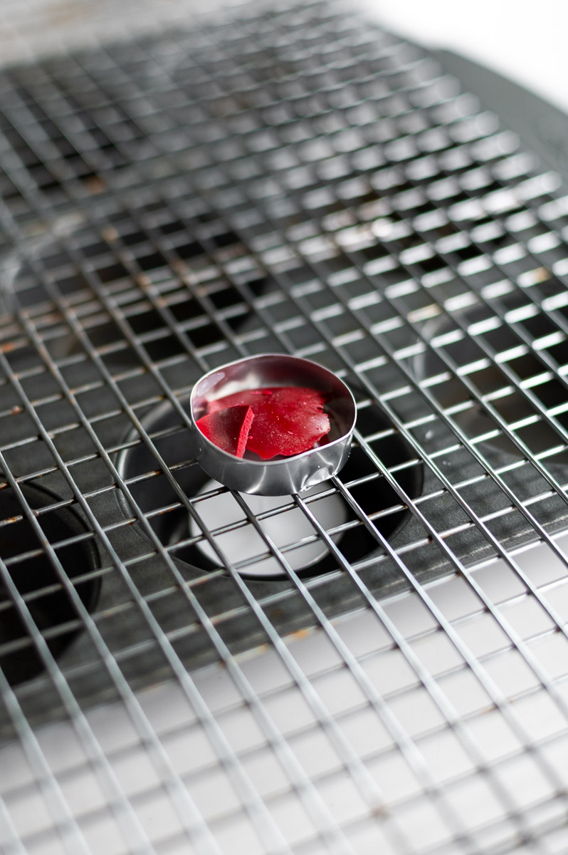 how to make an improvised wax warmer with a muffin tin, tea light, wire cooling rack and old spent tea light cup in order to create pin-drag drop pull wax designs on an easter egg