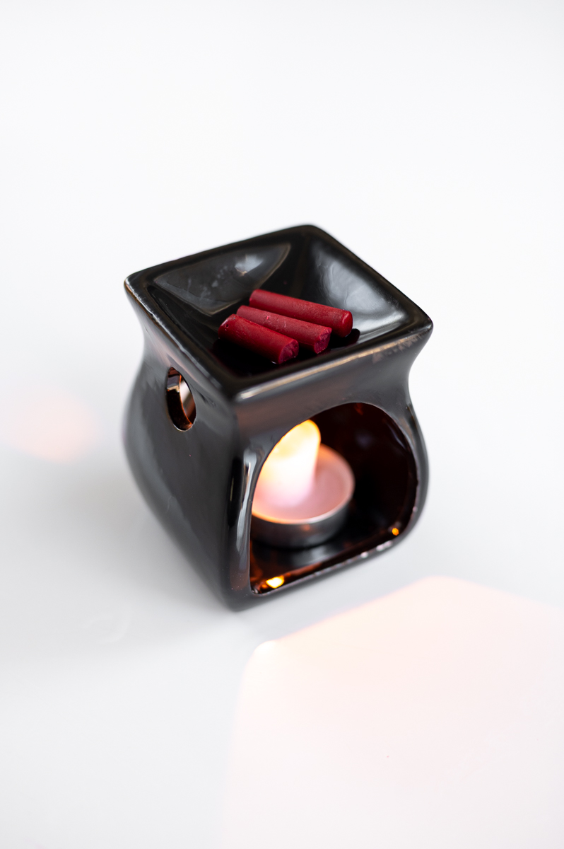 red crayon wax melts above a tea light candle in a fragrance warmer from the dollar tree in preparation for creating pin-drag wax Easter eggs.