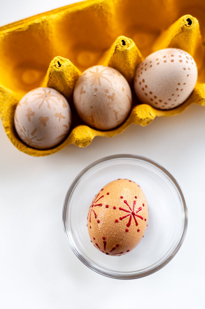 a collection of brown eggs that have been decorated with wax resist designs and then bleached lighter with vinegar.
